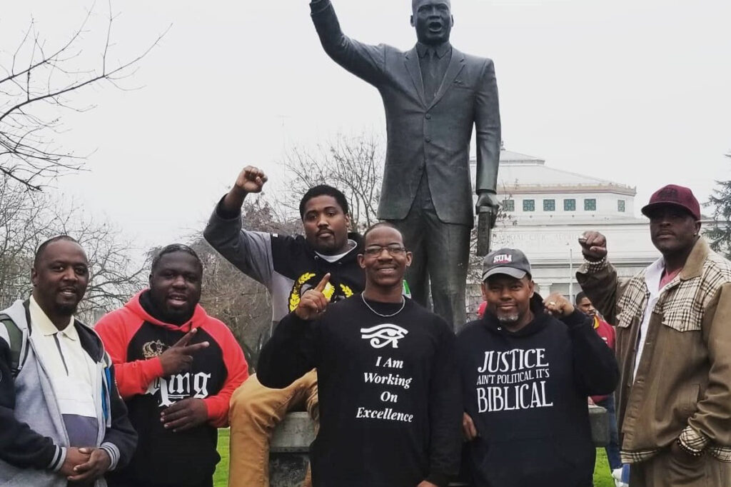 Pastor Curtis Smith with other organizers in front of a statue of Dr. Martin Luther King Jr.